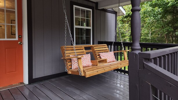 A porch with a wooden swing, a red door, and a window. - Curve Cottage located on The Rattlesnake 192 just outside of Somerset.  (Somerset)