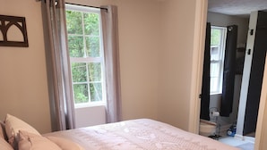 A bedroom with a large bed, a window with curtains, and a door leading to another room. - Curve Cottage located on The Rattlesnake 192 just outside of Somerset.  (Somerset)