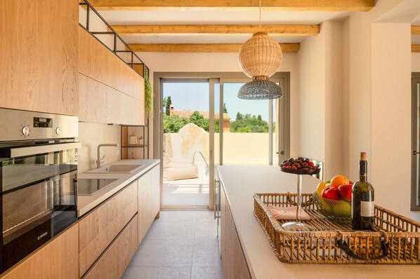 A modern kitchen with a built-in oven, a sink, and a large window. - Idyllic Escape: 2BR Corfu Villa, Heated Pool, 7 Mins to Airport (Kouramades)