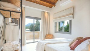 A bedroom with a bed, a window, a balcony, and a shelf with towels. - Secluded Charm: Abournela, Kouramades, Corfu - Aircon, Smart TV, Tavernas (Kouramades)