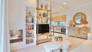 A modern living room with a TV, shelves, a round mirror, and a dining area. - Secluded Charm: Abournela, Kouramades, Corfu - Aircon, Smart TV, Tavernas (Kouramades)