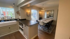 Une cuisine moderne dotée d’un îlot central, d’un coin repas agrémenté d’un grand miroir et offrant une vue sur l’extérieur grâce à une fenêtre.