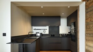 Una cocina moderna con armarios oscuros, piso de madera y horno empotrado.