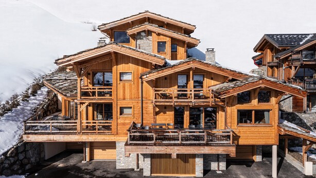 A multi-story wooden chalet with balconies, large windows, and a stone foundation. - Vue exceptionnelle ! Chalet moderne + sauna privé (Les Deux Alpes)