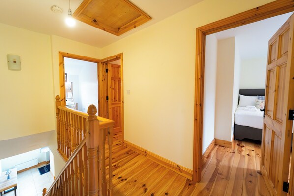 A wooden staircase leading to a bedroom with a bed and a nightstand.