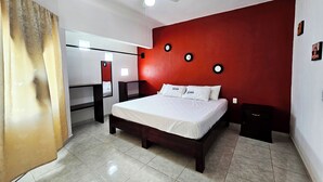A bedroom with a bed, a ceiling fan, a red accent wall, and a mirror. - Casa Santa Cecilia (Tehuacán)