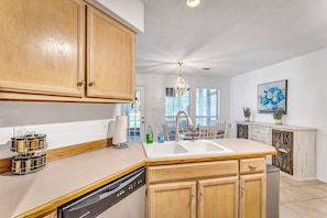 A kitchen with wooden cabinets, a dishwasher, a sink, and a chandelier. - New Listing Promo + Cruising the Coast (Ocean Springs)