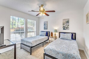 Un dormitorio con dos camas, ventilador de techo y televisor.
