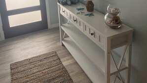 Huoneessa on valkoinen konsolipöytä, peili, lamppu ja pieni akvaario.