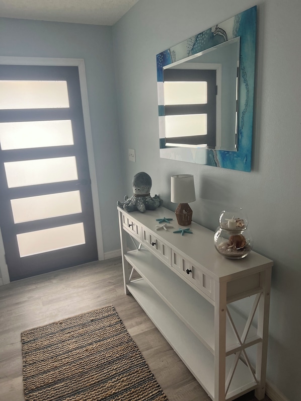A room with a white console table, a mirror, a lamp, and a small aquarium.