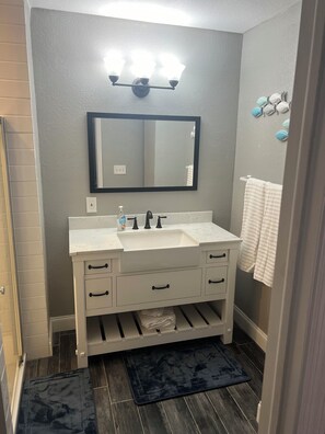 Un baño con tocador blanco, espejo y perchero.