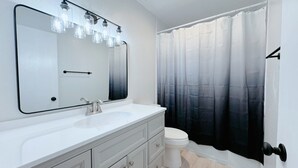A bathroom with a white sink, mirror, and toilet.