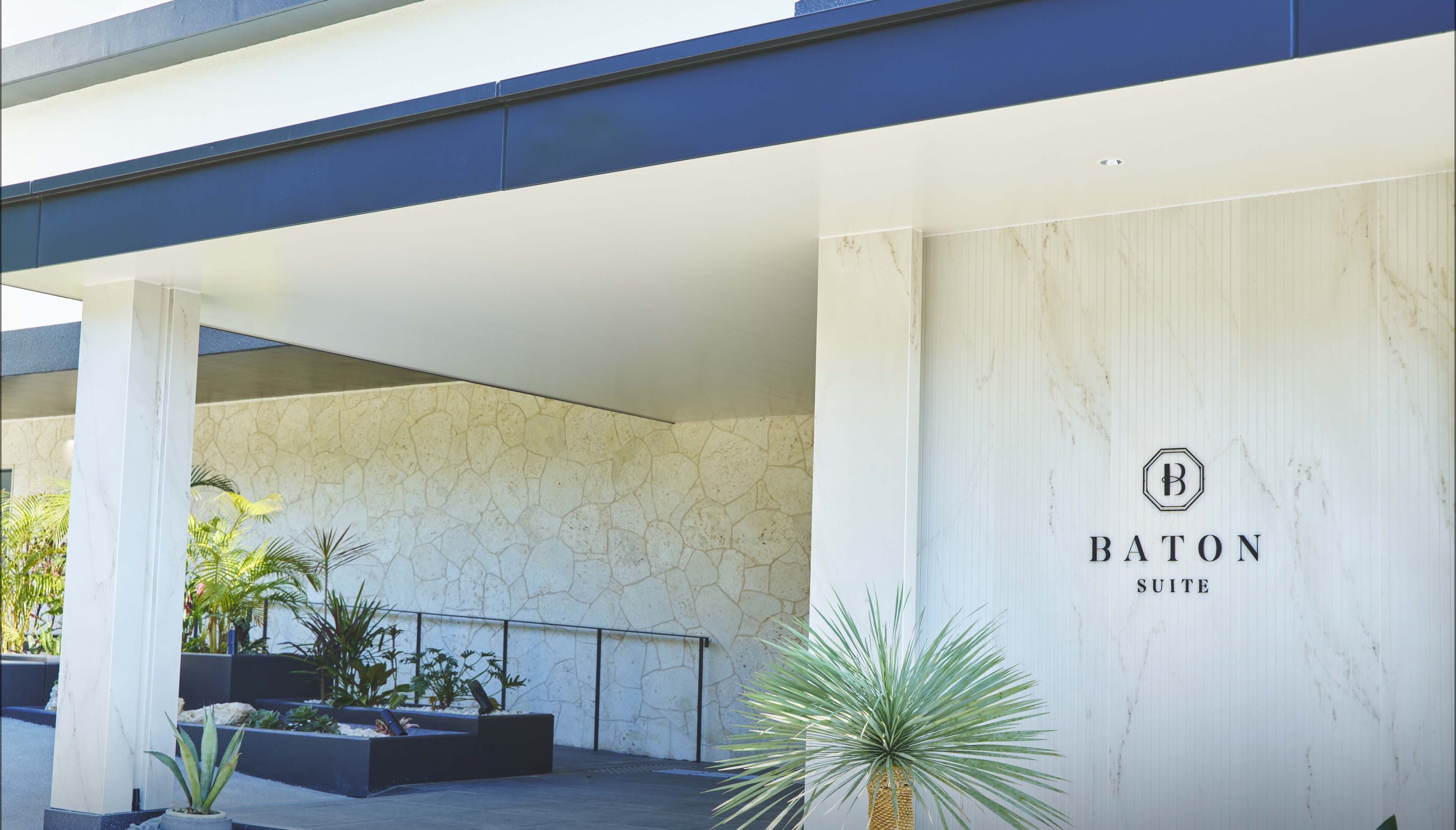 A modern building with a stone facade and a sign for 'BATON SUITE'.