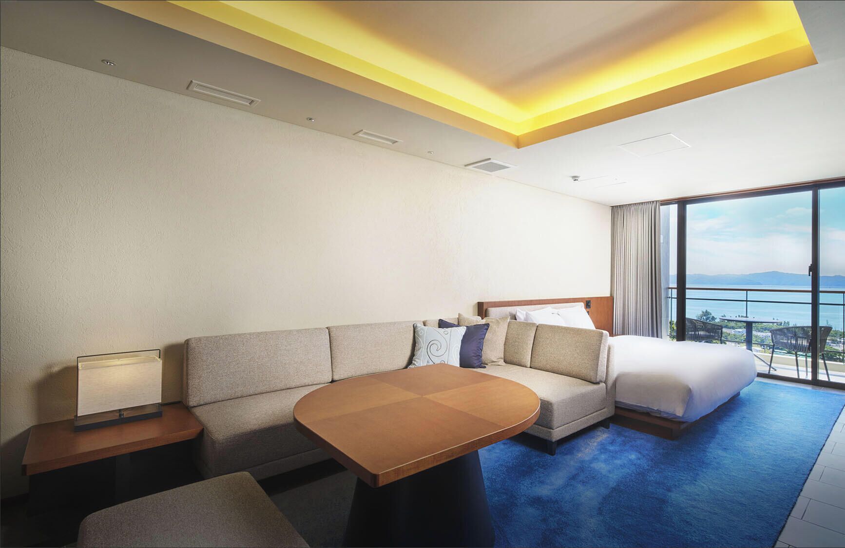 Ein Hotelzimmer mit Sofa, Bett, Tisch und Meerblick.