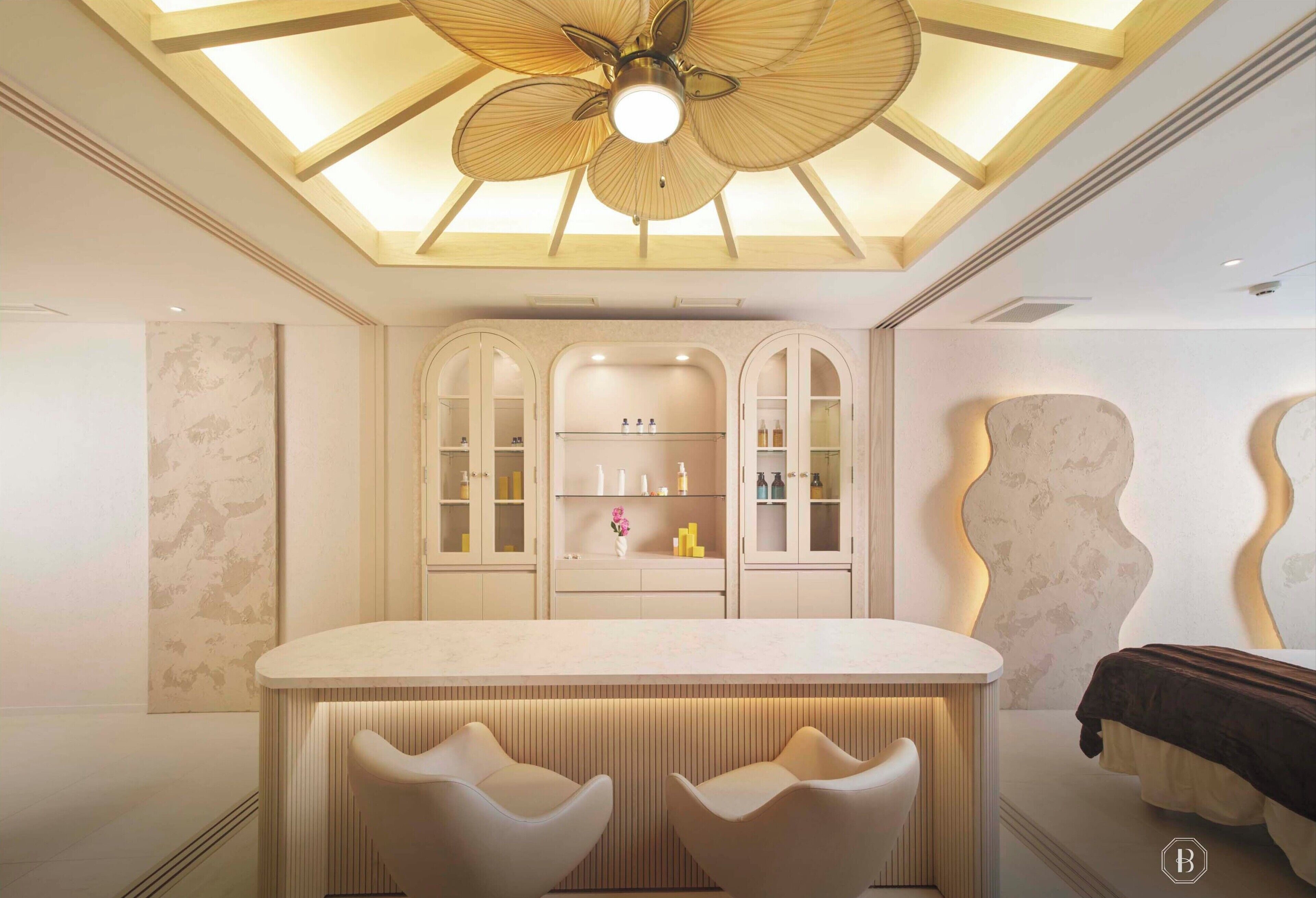 A modern bathroom with a skylight ceiling, a vanity with cabinets, and two chairs.