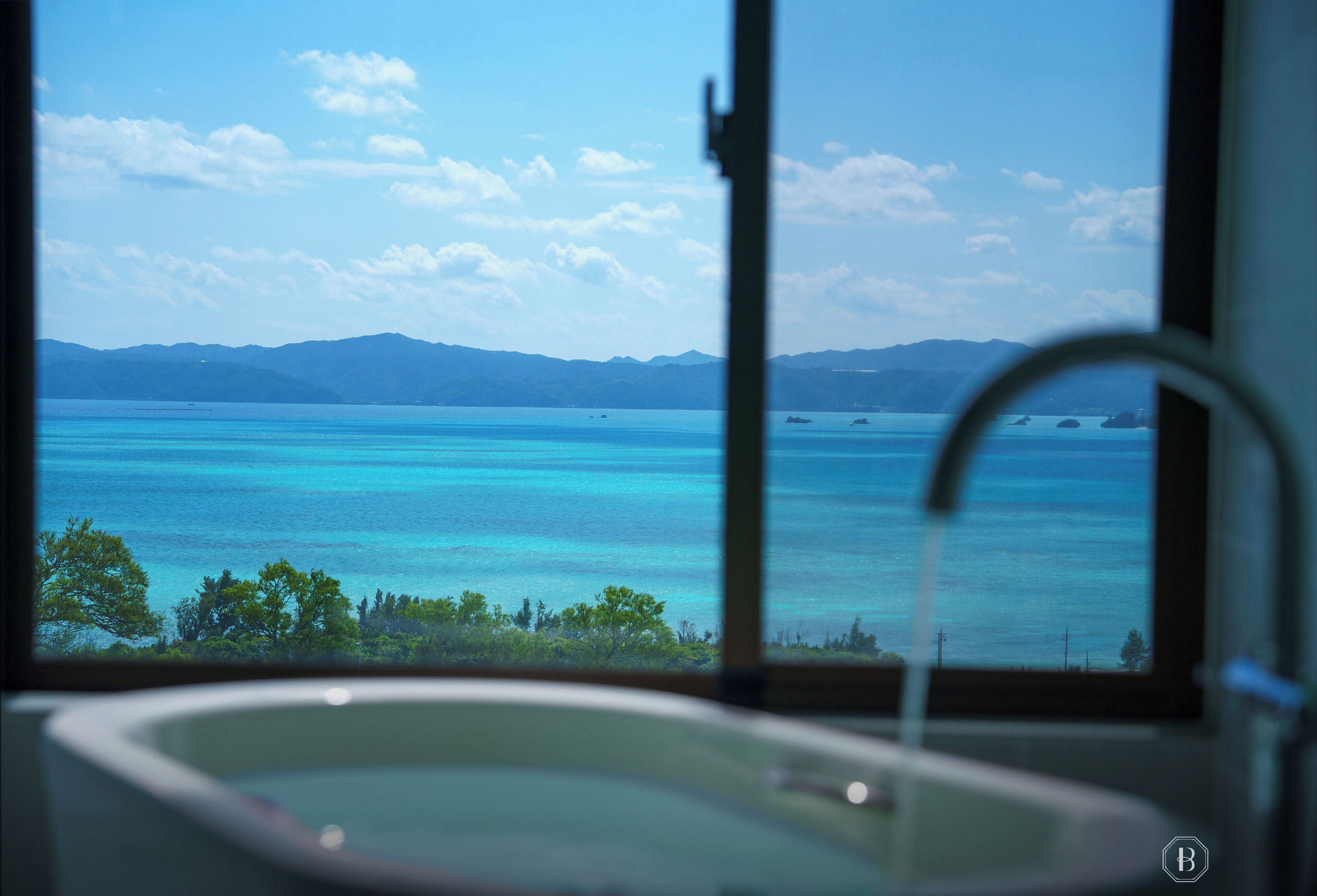 Casa de banho com vista para o mar azul-turquesa e montanhas.