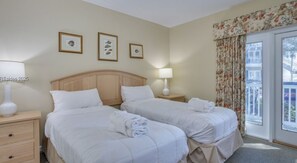 A hotel room with two beds, a wooden headboard, a nightstand with a lamp, and a window with floral curtains. - HHI Villa with WestinResort amenities, PLUS golf tennis pickleball included (Hilton Head Island)