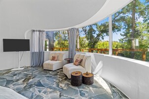 Una sala moderna con dos sofás, un televisor y un ventanal con vistas a una terraza de madera.