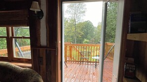 A wooden deck with a metal railing, a chair, and a table.