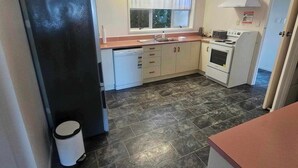 A compact kitchen with a refrigerator, stove, and sink. - Private Island Eco Retreat complete with resident Kiwi (Kerikeri)