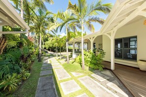 A covered outdoor area with a stone pathway, palm trees, and lush greenery. - Villa Big Blue, panoramic sea view and pool -5 rooms -Wifi (Le François)