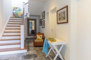 A staircase leading to a second floor, a wooden chair with a floral cushion, a small table with a hat, and framed pictures on the wall. - Villa Big Blue, panoramic sea view and pool -5 rooms -Wifi (Le François)