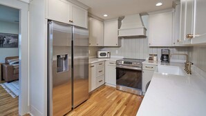 A modern kitchen with white cabinetry, stainless steel appliances, and a wooden floor. - Historic Cottage in Perry - 3 Bedroom 2 Bath (Perry)