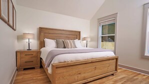A bedroom with a wooden bed, two bedside tables, and a window. - Historic Cottage in Perry - 3 Bedroom 2 Bath (Perry)