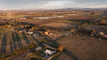 An aerial view of a rural landscape with fields, a small cluster of buildings, and a road.
