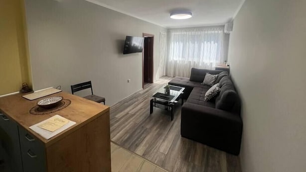 Una sala de estar moderna con un sofá, una mesa de centro y un televisor montado en la pared.