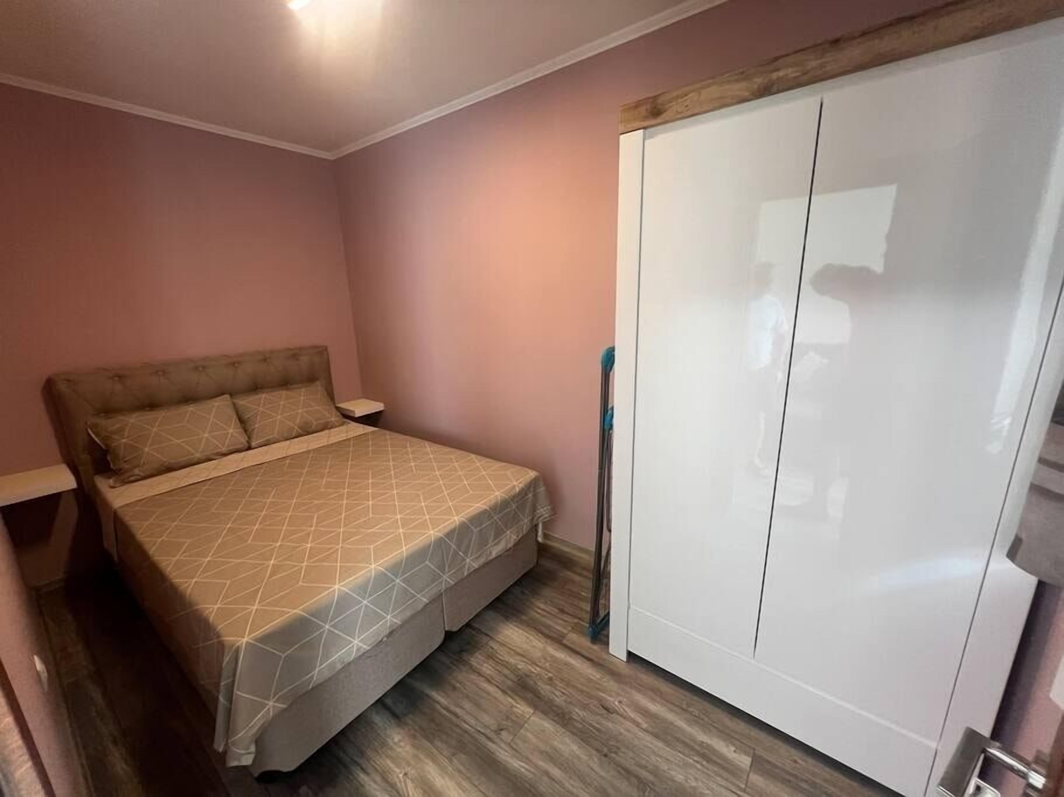 A bedroom with a bed, a wardrobe, and a nightstand.