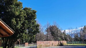 A park with a paved walkway, a wooden structure, and a brick wall. - Cabin 1 - Aires del Sur Pucón (Pucon)
