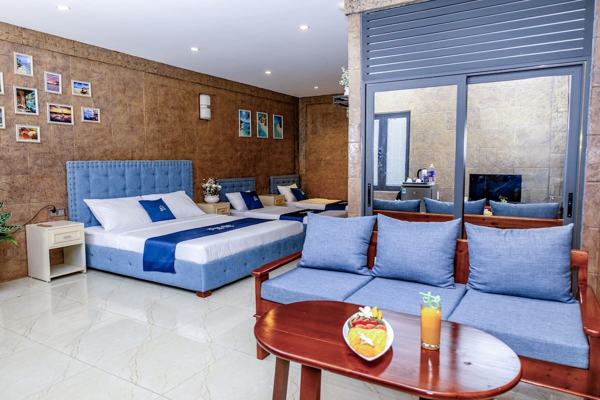 Een hotelkamer met een groot bed, een bank, een klein tafeltje met een schaal fruit en drankjes, en een televisie.