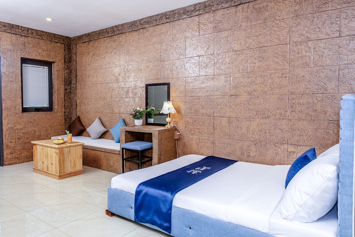 Hotelkamer met een bed, bureau, stoel, klein tafeltje en raam.
