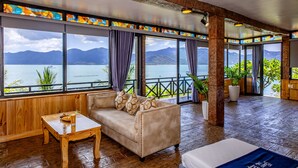 Quarto com sofá, mesa e vista para um lago e montanhas.