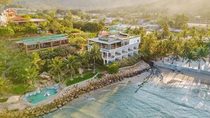 Resort com piscina, praia e montanhas ao fundo.