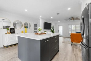 A modern kitchen with a central island, dark cabinetry, and a large refrigerator. - Tropical Oasis with Heated Pool and Cabana Bar (Oakland Park)