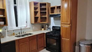 A kitchen with wooden cabinets, a stove, a sink, and a trash can. - Renovated schoolhouse loft (Morgantown)