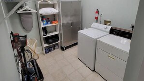 A laundry room with a washing machine, dryer, shelves with cleaning supplies, and a fire extinguisher. - Renovated schoolhouse loft (Morgantown)