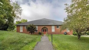 A brick building with a red door and a small front yard. - Renovated schoolhouse loft (Morgantown)