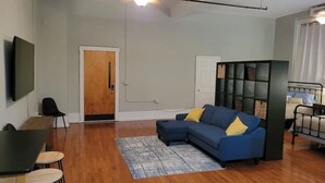 A living room with a sectional sofa, a coffee table, and a TV mounted on the wall. - Renovated schoolhouse loft (Morgantown)