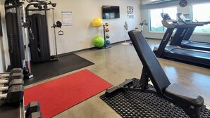 Un gimnasio con equipo de ejercicio, cintas de correr y una frase motivacional en la pared.