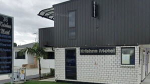 A modern building with a sign for "Krishna Motel" and a small attached structure. - Krishna Motel (Papakura)