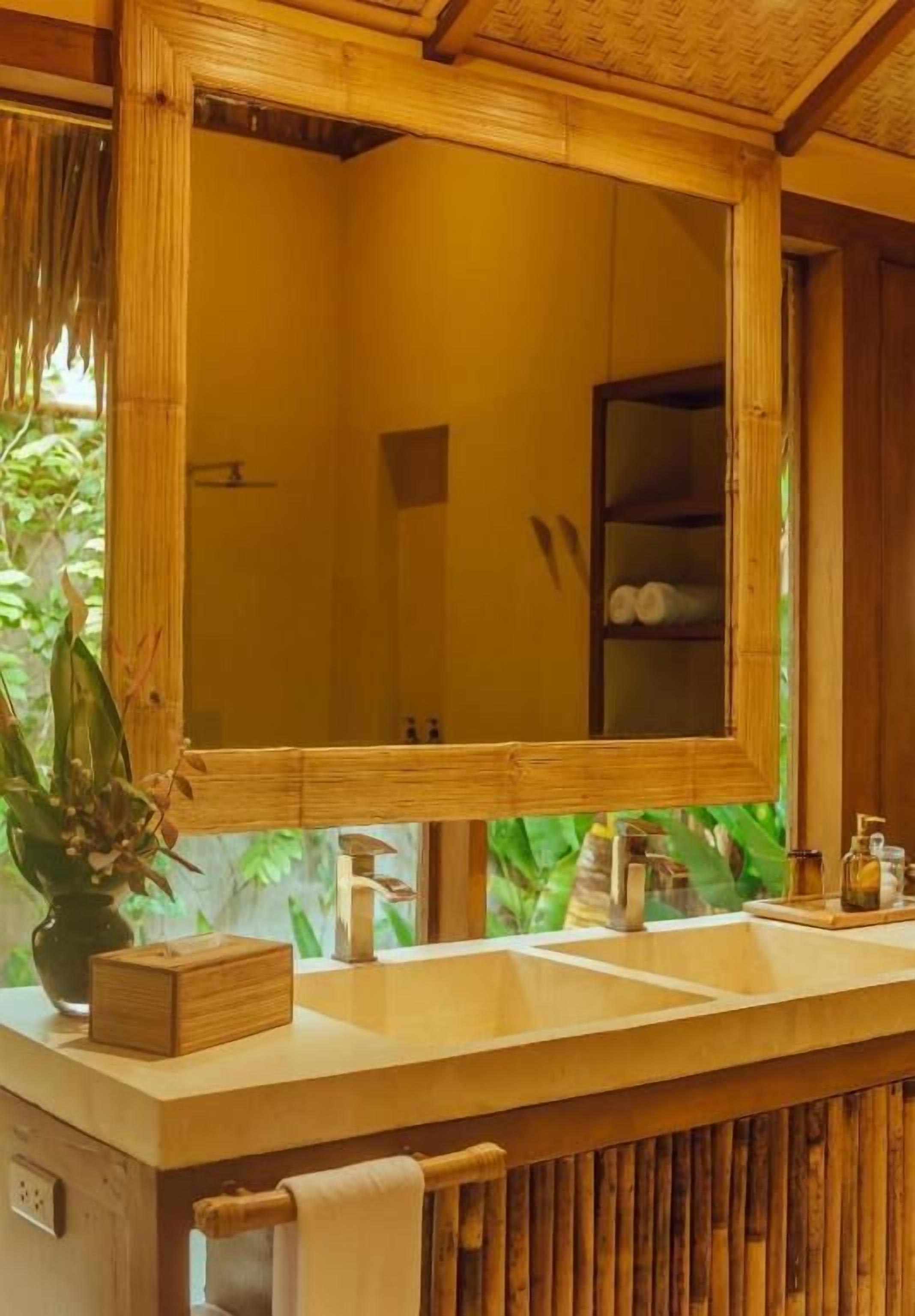 Ein Badezimmer mit einem Holzbadschränken, einem großen Spiegel und einem Ablagebereich für Toilettenartikel.