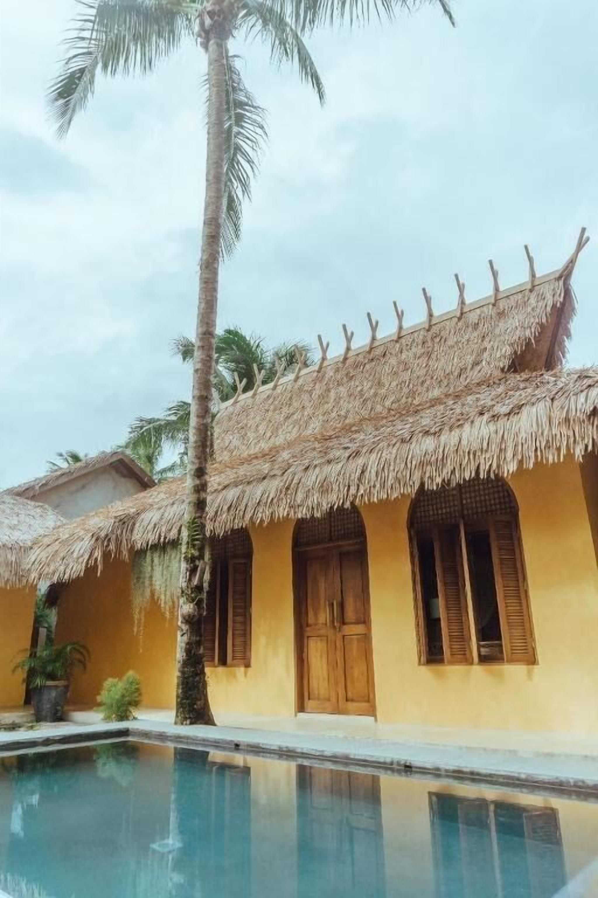 Edificio con techo de paja, ventanas de madera y piscina delantera.