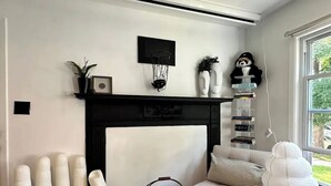 Una sala de estar con chimenea, un sofá, un sillón grande de color blanco y un tapete estampado.