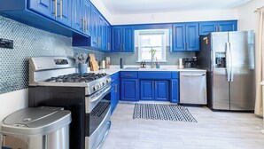 Una cocina moderna con armarios azules, electrodomésticos de acero inoxidable y un salpicadero con diseño.
