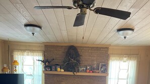 A living room with a fireplace, a sofa, a television, and a ceiling fan.