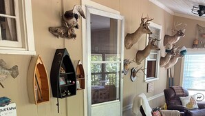 A cozy living room with a patterned sofa, a wooden boat shelf, and various deer antlers on the walls.