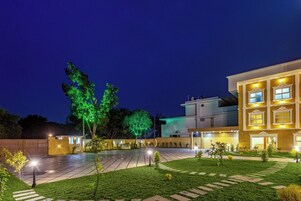 A courtyard with a paved walkway, a well-maintained lawn, and a building with multiple windows and balconies.